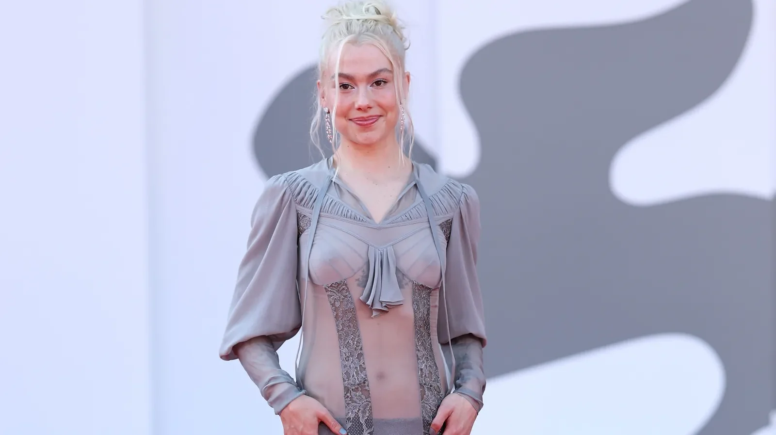 Phoebe Bridgers wearing a sheer gray McQueen lace gown on the red carpet at the 2026 Venice Film Festival