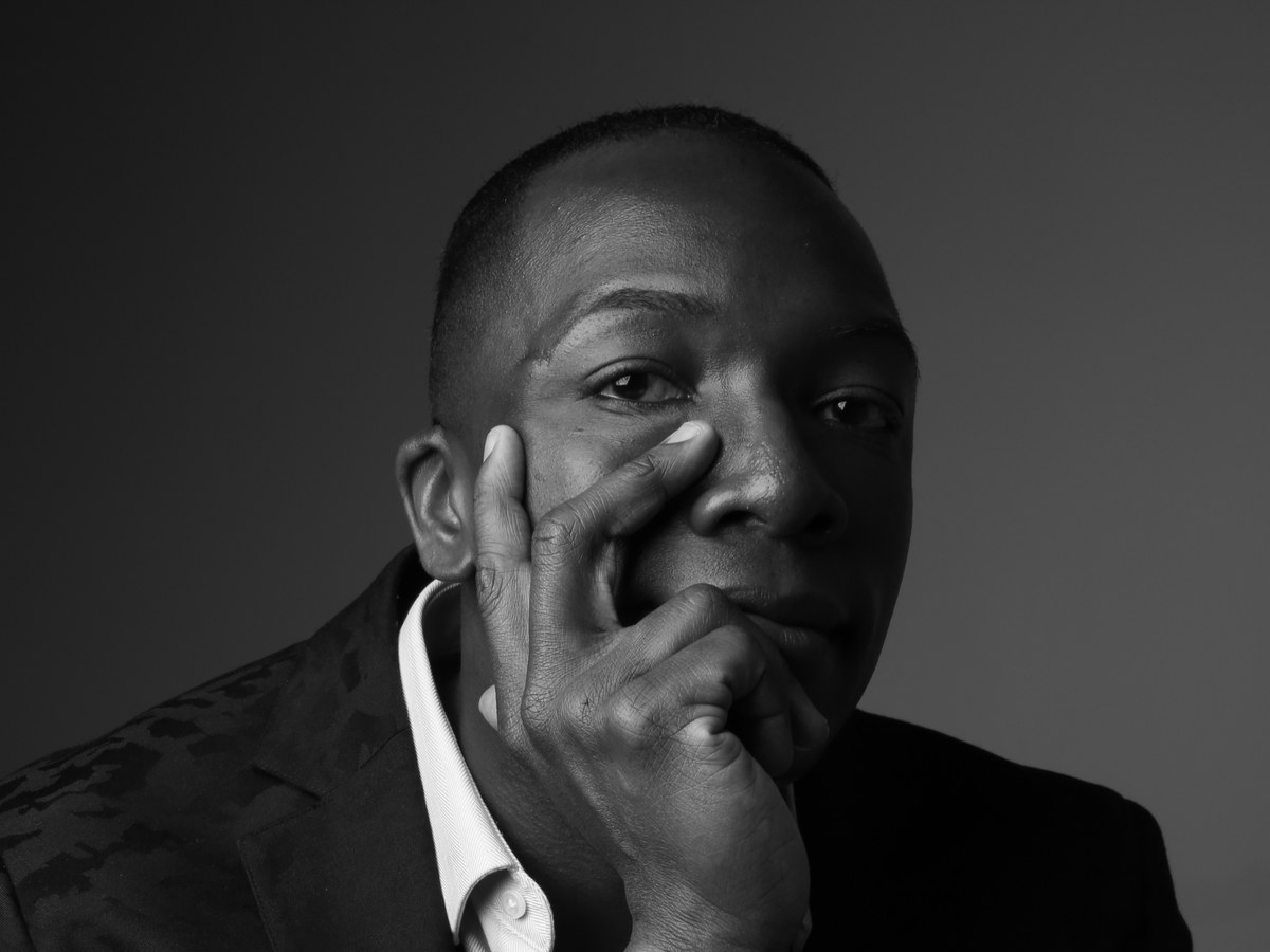 Darshae Kiér in a black-and-white portrait, hand resting against his face