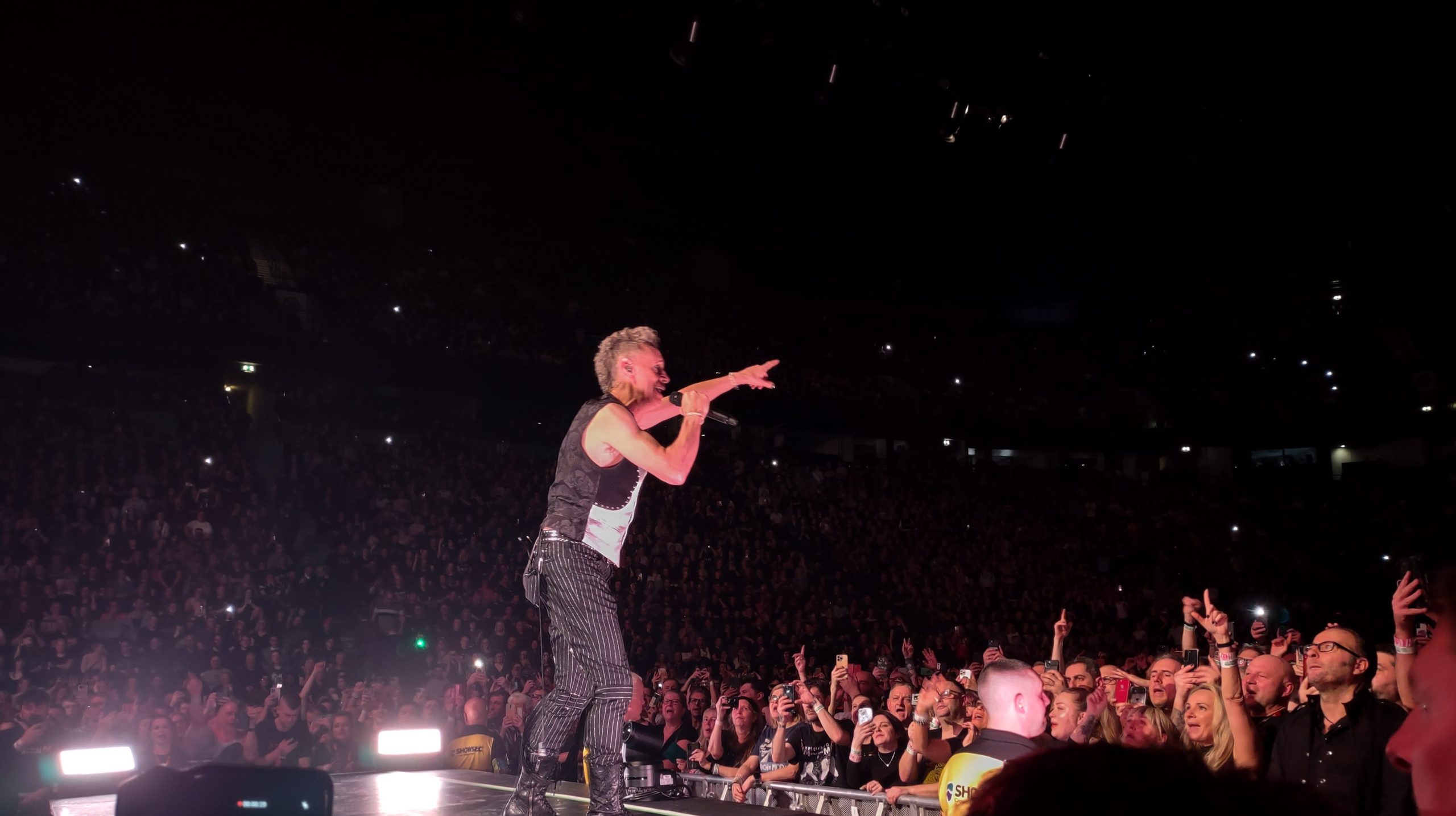 Martin Gore performing with a microphone onstage in Manchester