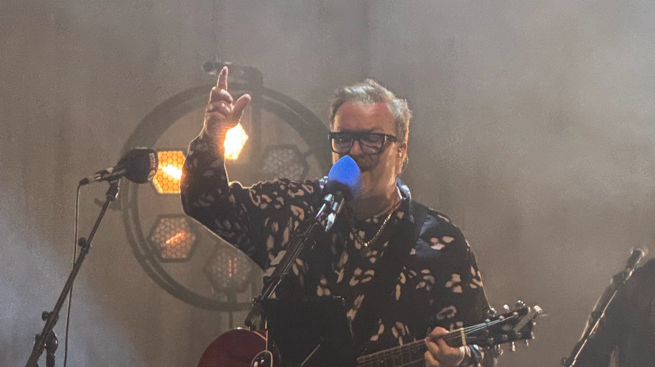 Jez Williams playing guitar and singing into a microphone